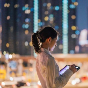 Woman working on a tablet in a city at night