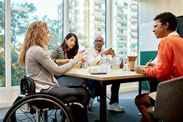 A diverse group of individuals sitting around a table, discussing.