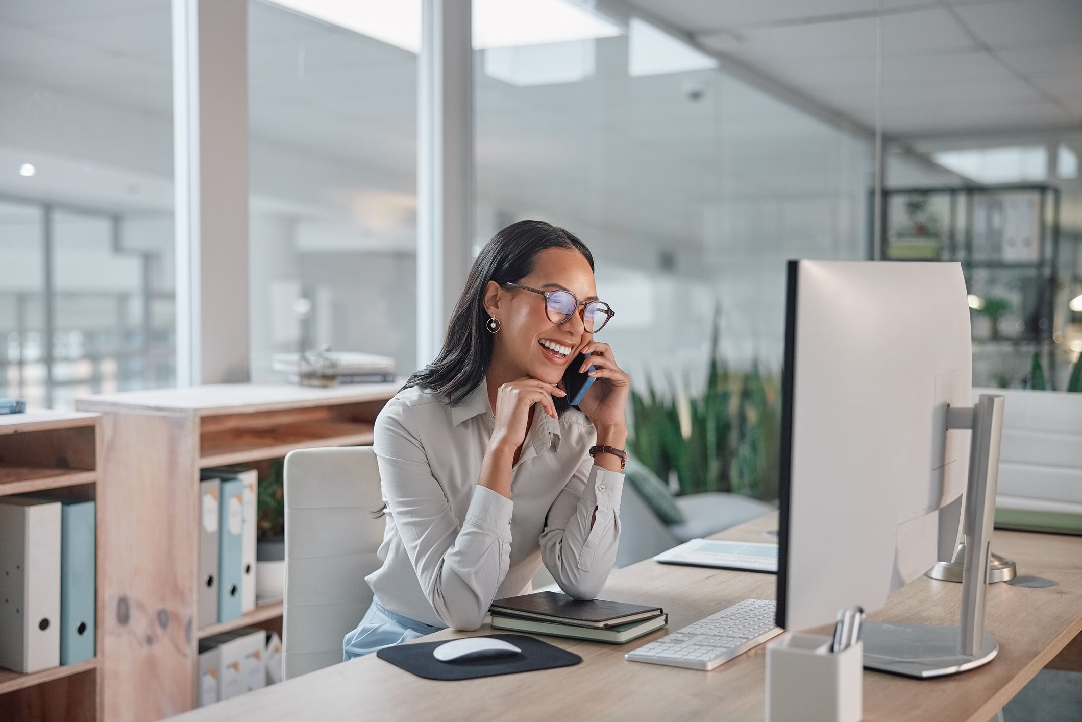 Woman smiling at computer while taking phone call
