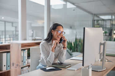 Woman smiling at computer while taking phone call