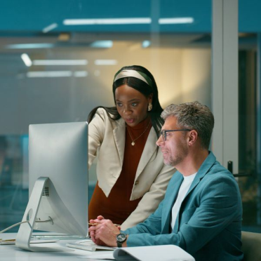 Woman pointing to screen that a man is working on